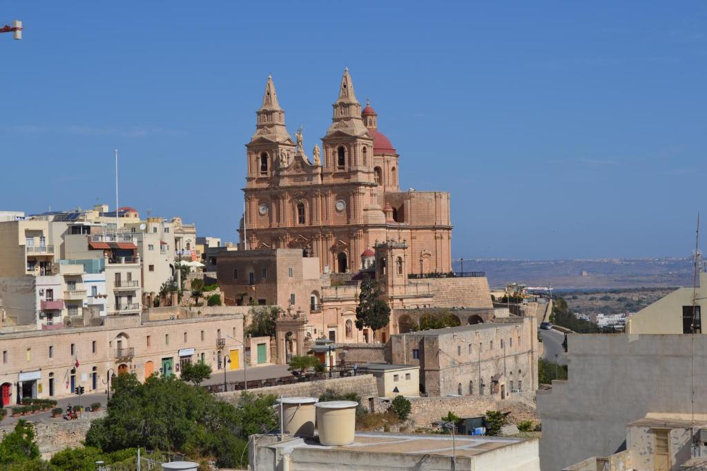 een oud gebouw bovenop een heuvel met gebouwen bij Mellieha Town Centre Bright & Spacious 3 Bedroom Apartment in Mellieħa