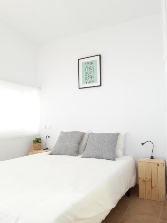 コニル・デ・ラ・フロンテーラにあるCH II Apartments ZONA DE OCIO NOCTURNOの白いベッドと壁の絵が備わる白いベッドルーム1室