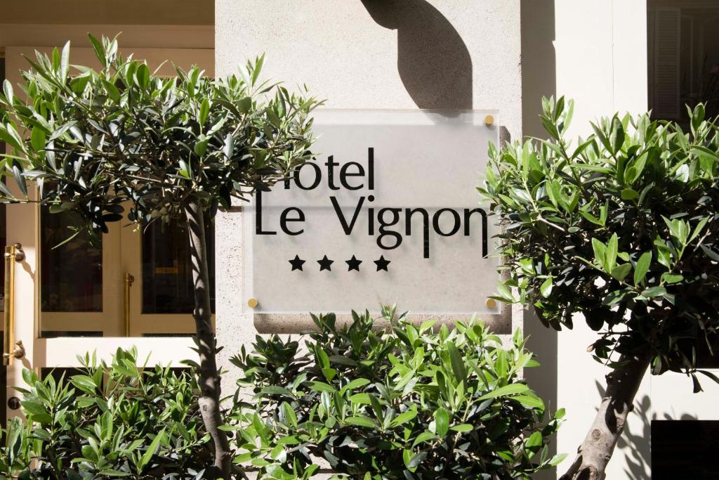 um sinal em frente a um edifício com árvores em Hotel Vignon em Paris