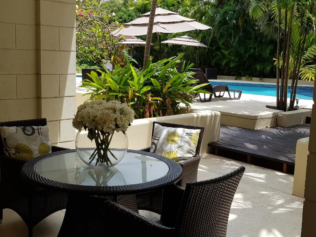 a glass table with a vase of flowers on a patio at Brownes Condominium 1 in Bridgetown