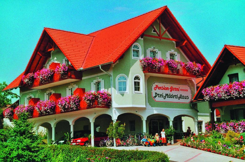 a building with an orange roof with flower boxes on it at Pension Drei-Mäderl-Haus in Unterlamm
