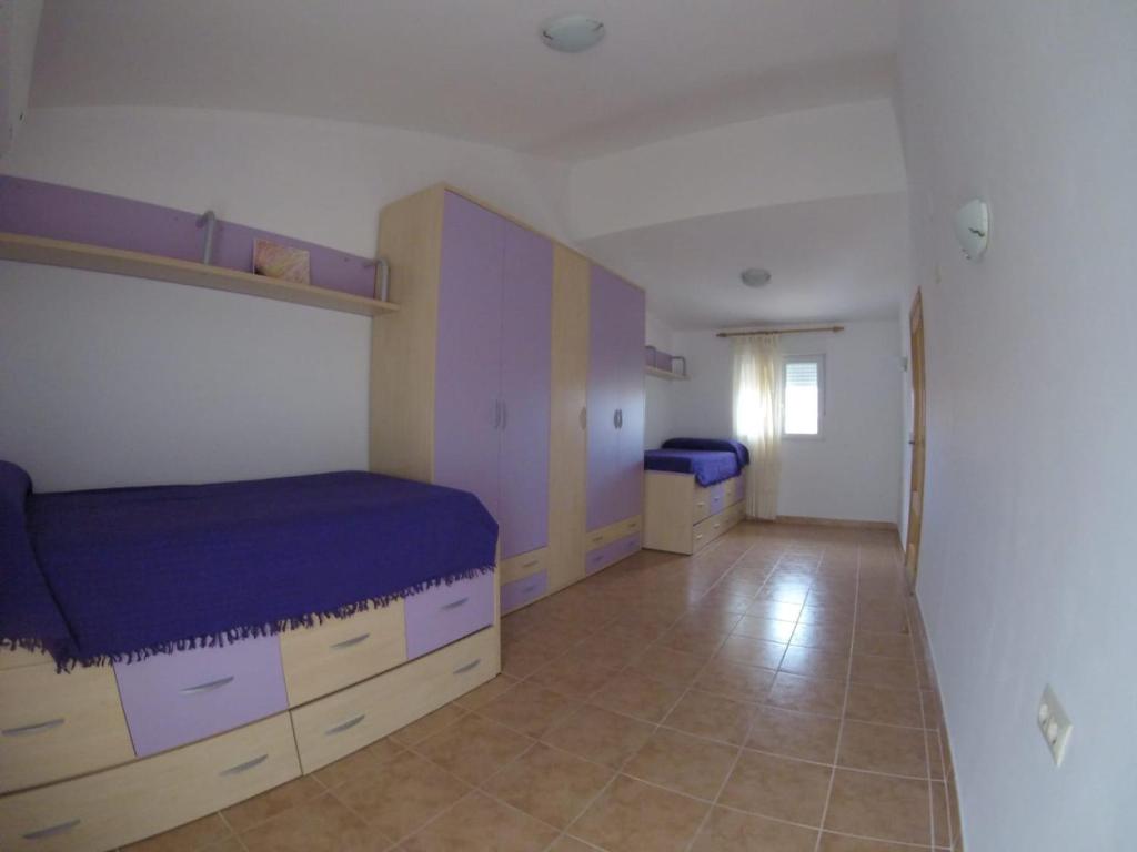 ペニスコラにあるChalet Briのベッドルーム1室(紫のシーツとキャビネット付きのベッド1台付)