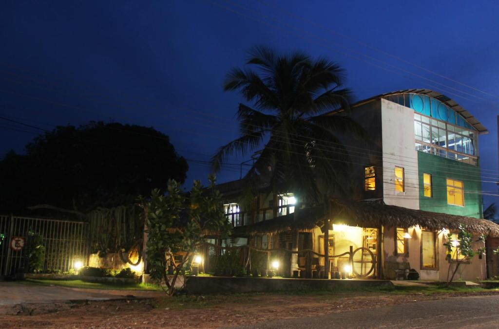 a building with a palm tree behind it at night at Solar das Gaivotas Pousada in Barreirinhas
