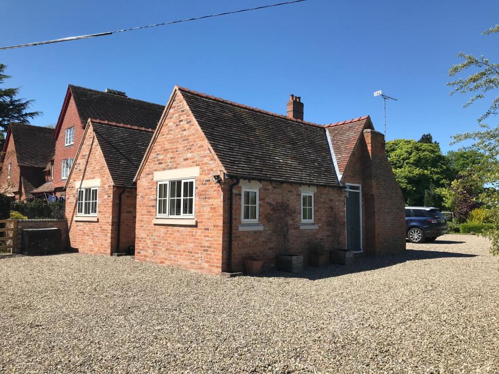 a red brick house on a gravel driveway at Pheasant Cottage in Tarporley