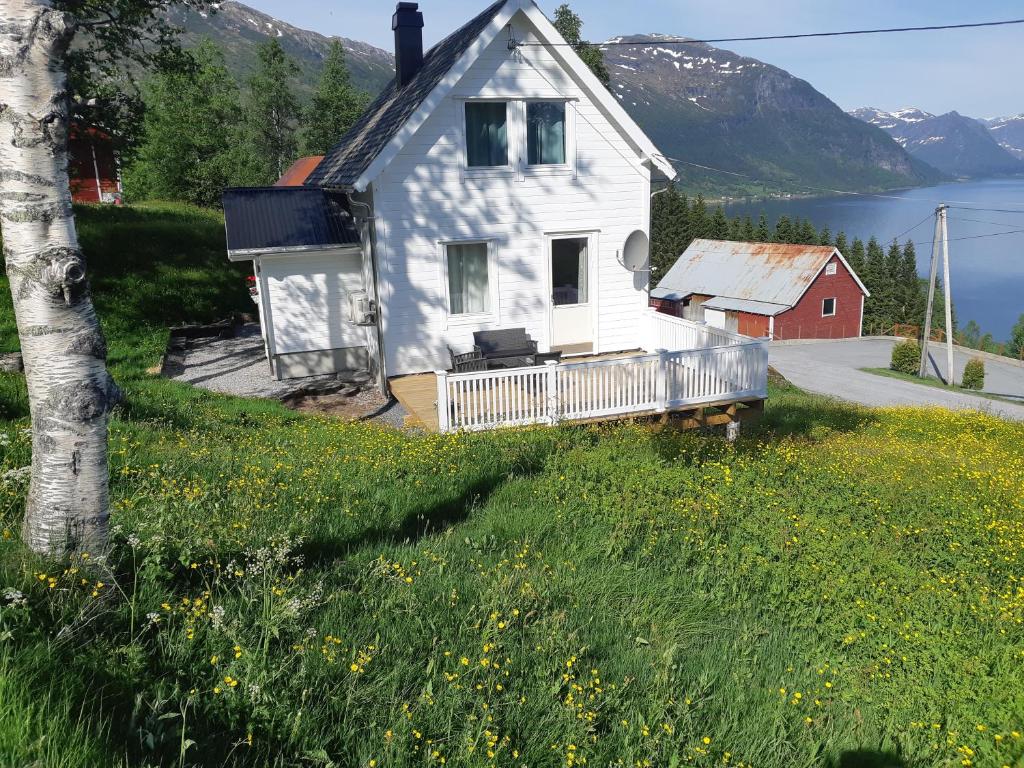 uma casa branca numa colina ao lado de um corpo de água em Haukedalen Feriehus em Viksdalen