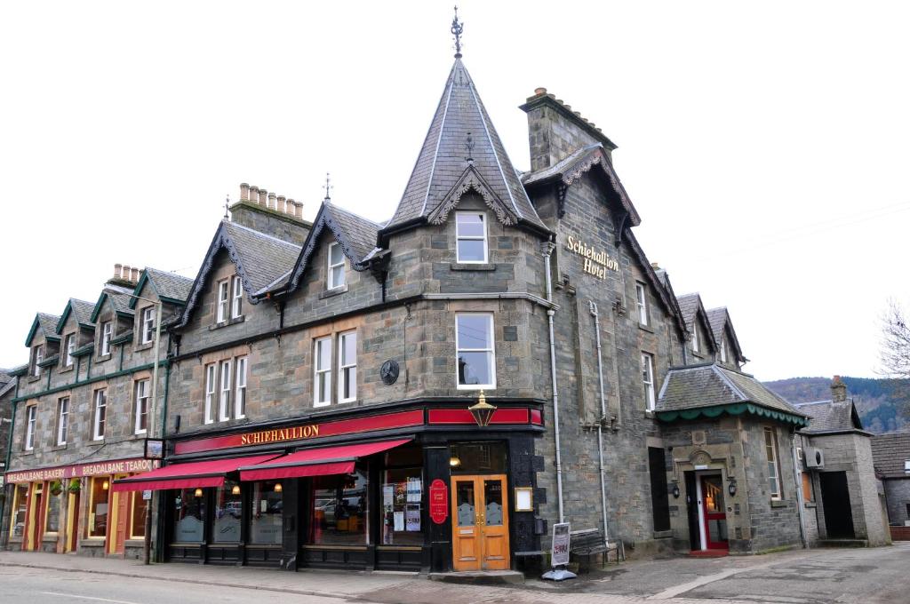 un antiguo edificio de piedra en la esquina de una calle en Schiehallion Hotel, en Aberfeldy