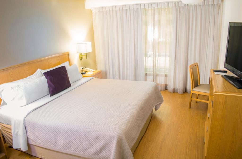une chambre d'hôtel avec un lit et une télévision dans l'établissement iStay Hotel Monterrey Histórico, à Monterrey