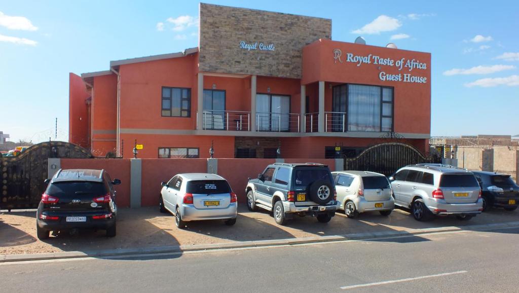 een groep auto's geparkeerd op een parkeerplaats voor een gebouw bij Royal Castle Guest House in Windhoek