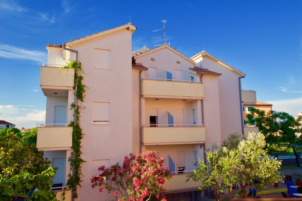 a white building with trees in front of it at Apartmani HRGA in Vodice