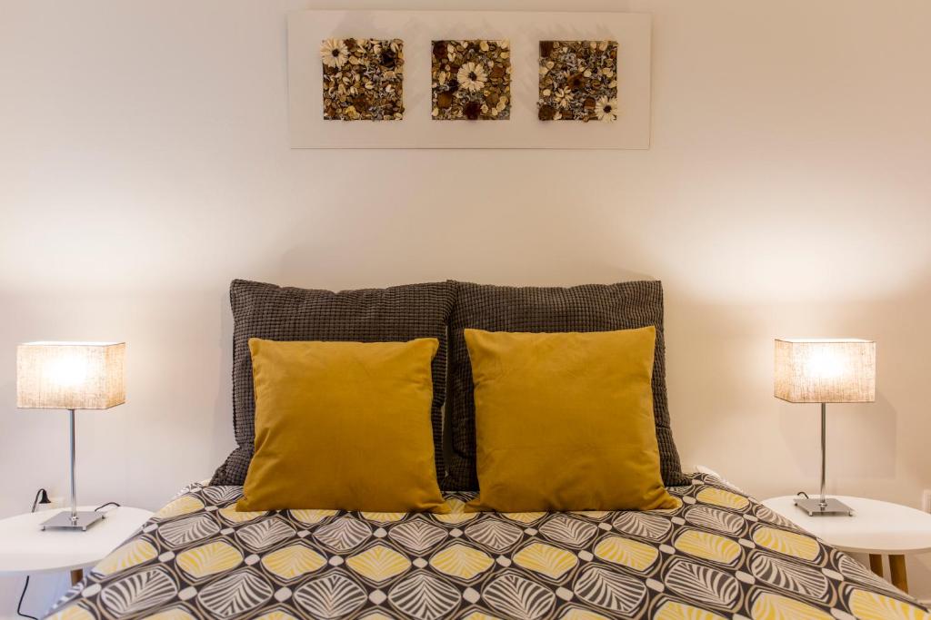 um quarto com 2 candeeiros e uma cama com almofadas amarelas em Casa Oliveira in Downtown Porto II em Porto