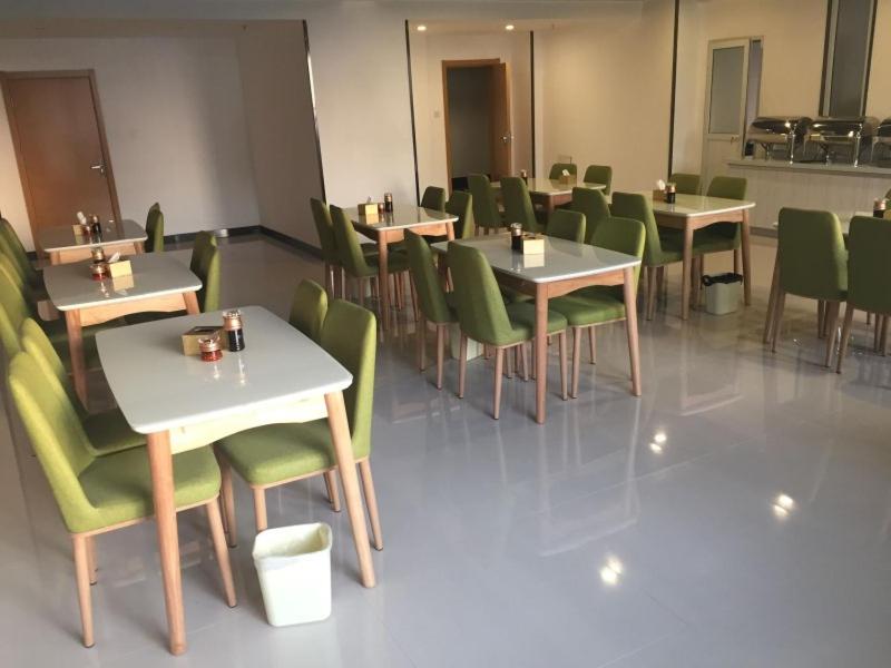 a dining room with tables and green chairs at Vatica Xingtai Qiaoxi District Yongkang Street Technical College Hotel in Xingtai