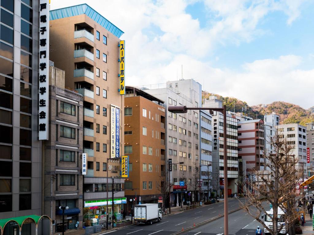 Eine Stadtstraße mit hohen Gebäuden und einer Straßenlaterne in der Unterkunft Super Hotel Kobe in Kōbe