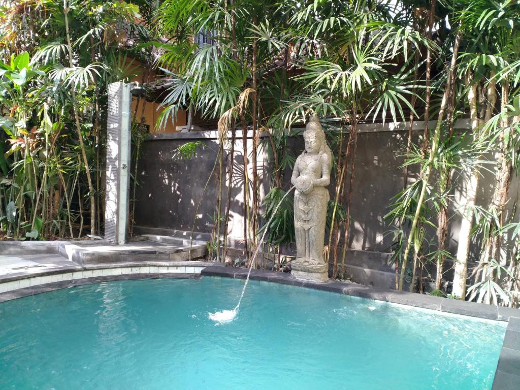 a fountain in a swimming pool with a statue at Pondok Bambu Homestay in Ubud