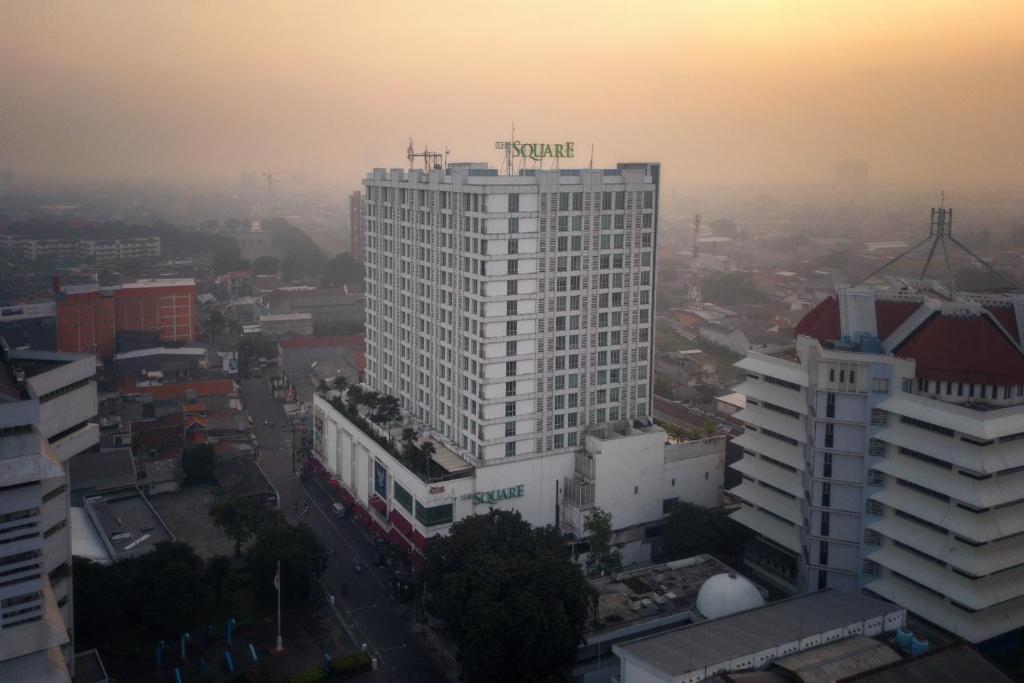 The Square Surabaya Hotel في سورابايا: مبنى أبيض طويل في مدينة عند غروب الشمس