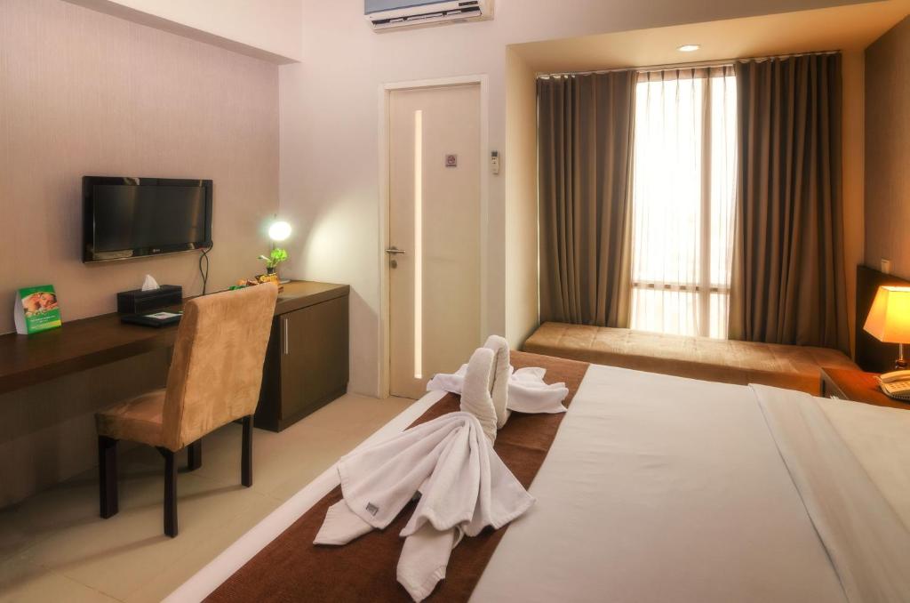 Postel nebo postele na pokoji v ubytování The Square Surabaya Hotel