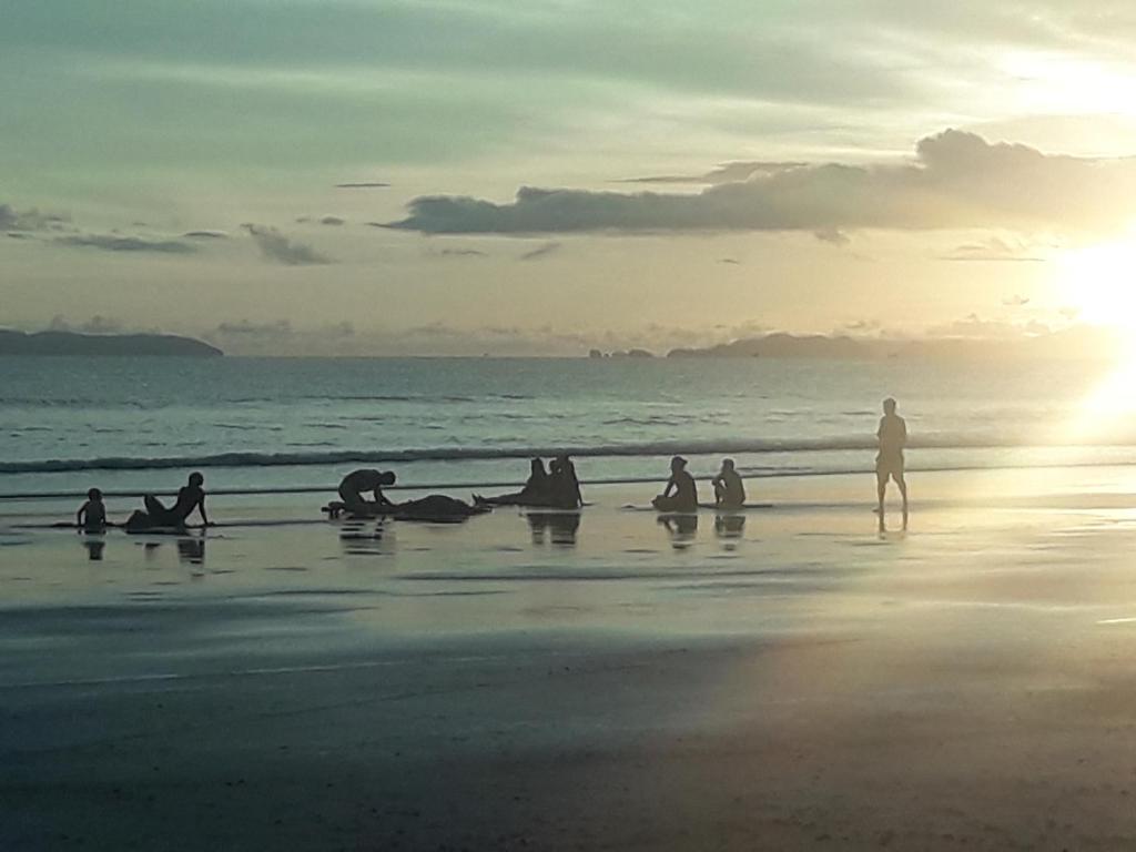 a group of people on the beach at sunset at JJ Beach Resort & JJ Seafood in Ko Phayam