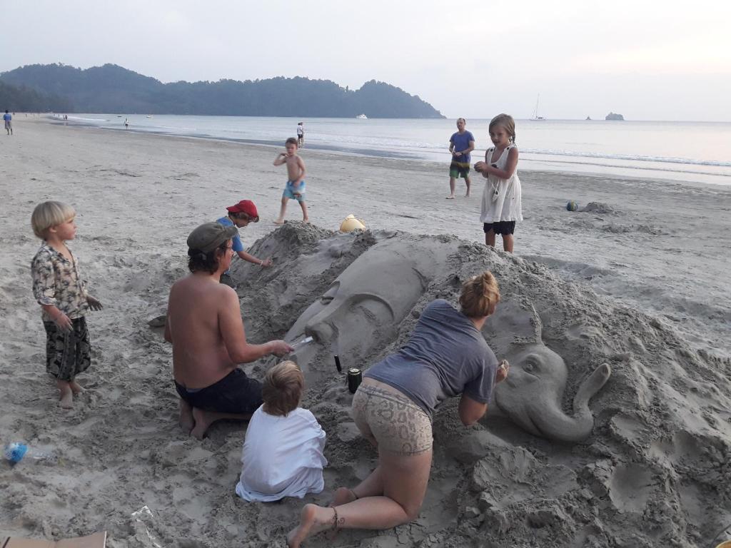 a group of people building an elephant sand sculpture on the beach at JJ Beach Resort & JJ Seafood in Ko Phayam