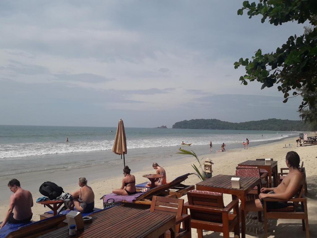a group of people sitting at tables on the beach at JJ Beach Resort & JJ Seafood in Ko Phayam