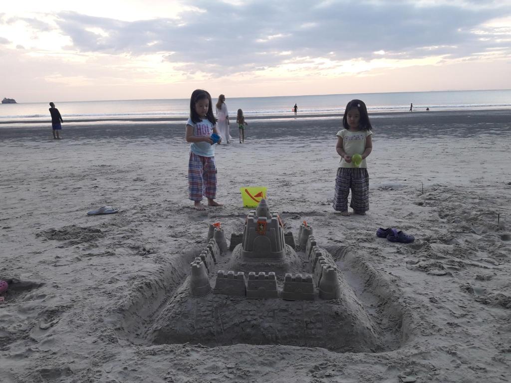 two girls standing in front of a sand castle on the beach at JJ Beach Resort & JJ Seafood in Ko Phayam