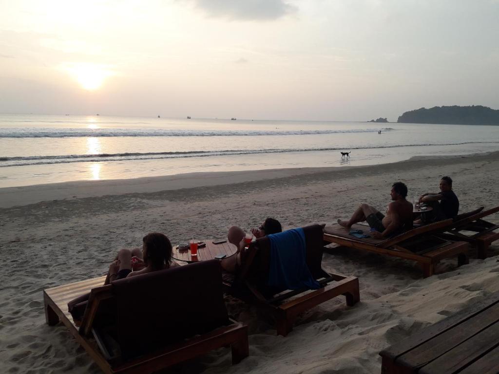 a group of people sitting on the beach watching the sunset at JJ Beach Resort & JJ Seafood in Ko Phayam