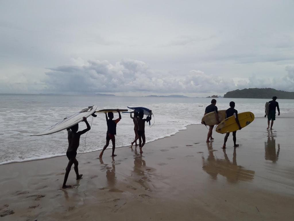 a group of people holding their surfboards on the beach at JJ Beach Resort & JJ Seafood in Ko Phayam