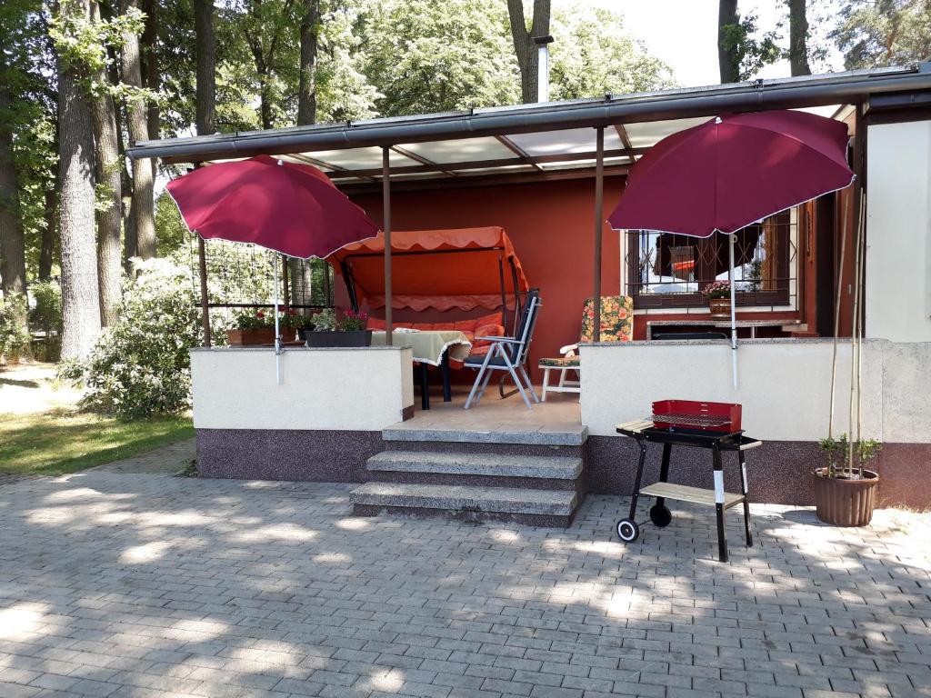 a house with two red umbrellas and a table at Ferienhaus direkt am See in Bad Saarow