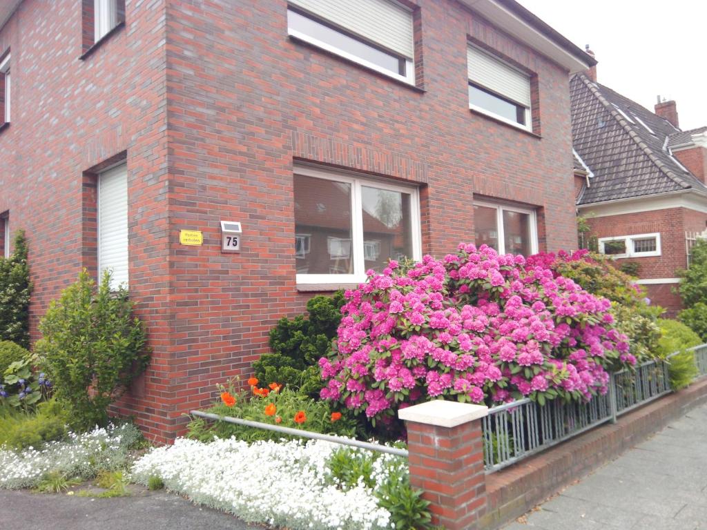 a brick house with pink flowers in front of it at Wind & Wasser in Emden