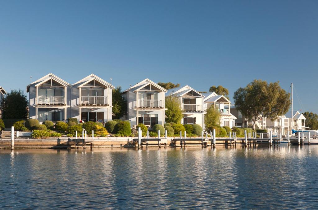 a row of houses on a dock next to the water at Captains Cove Resort - Waterfront Apartments in Paynesville