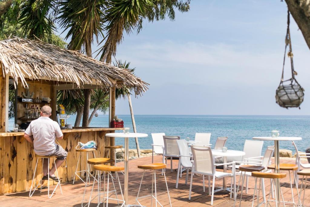 a man sitting at a bar on the beach at Elya Beach Luxury Suites in Ayios Theodhoros