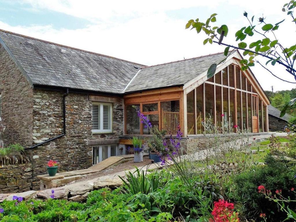 an external view of a stone house with a conservatory at The Cider Barn at Home Farm in Wembury