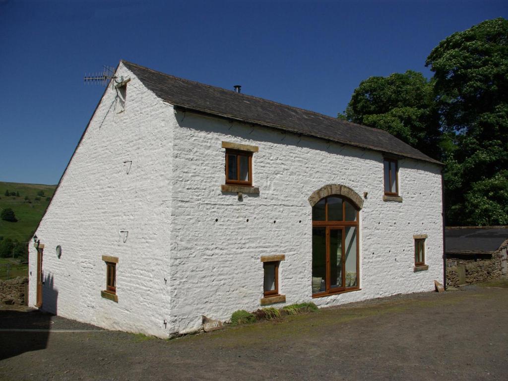a white building with windows on the side of it at Middlefell View Cottage in Alston
