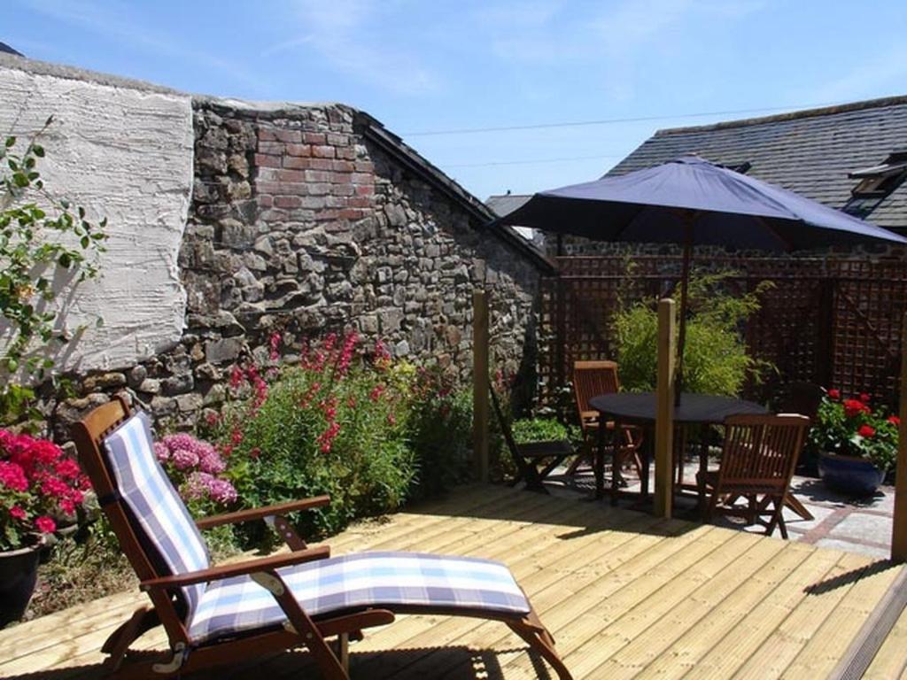 a wooden deck with a table and an umbrella at Millers Cottage in Bude