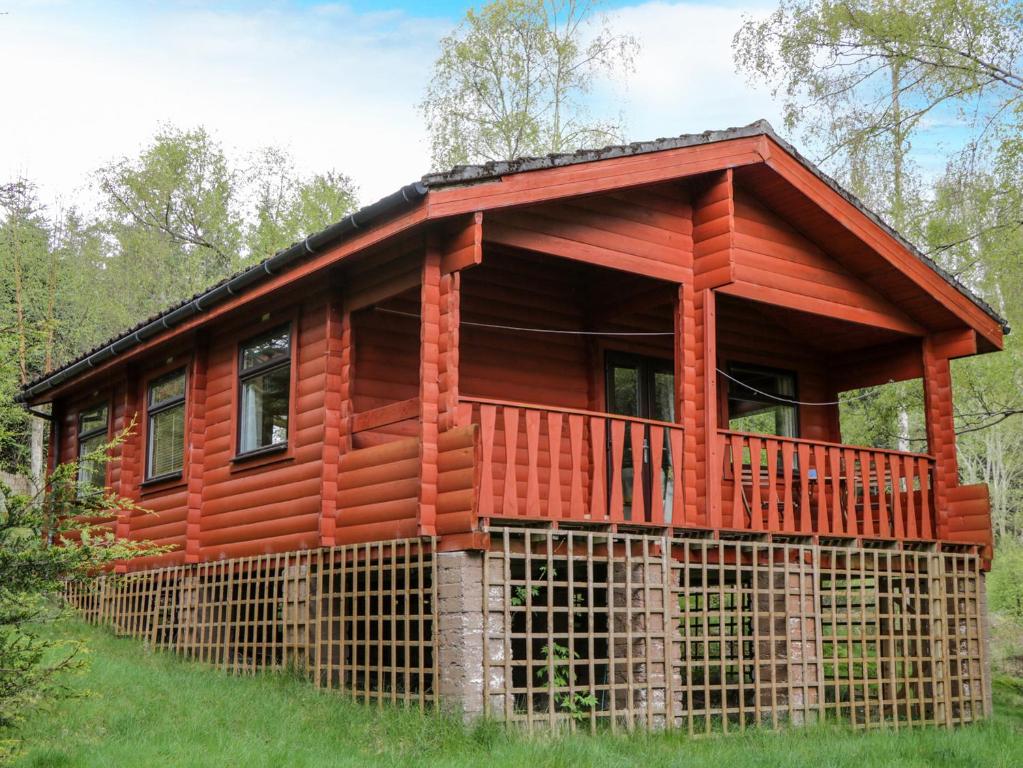 a log cabin with a wrap around porch at Eagle Lodge in Strathpeffer