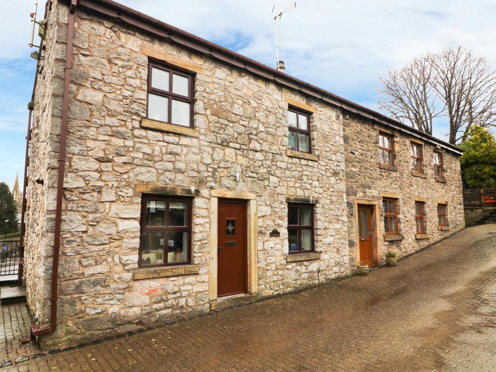 un antiguo edificio de piedra con puertas marrones en una calle en 1 The Stables en Clitheroe