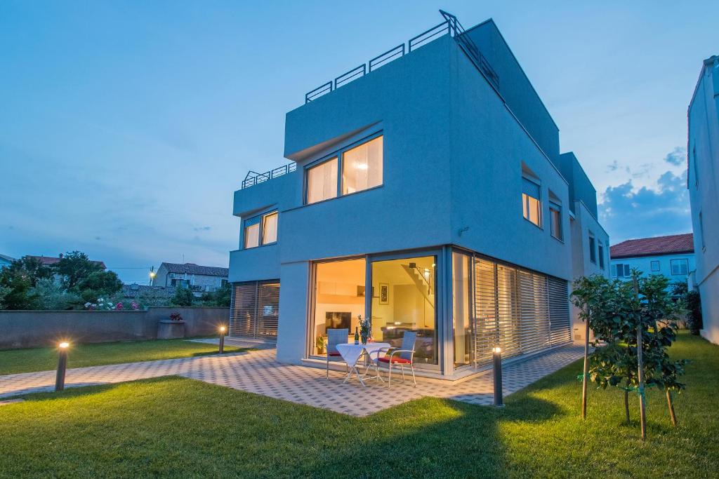 a blue house with a lawn in front of it at CAISA- luxury apartment 20 m from the sea in Zadar