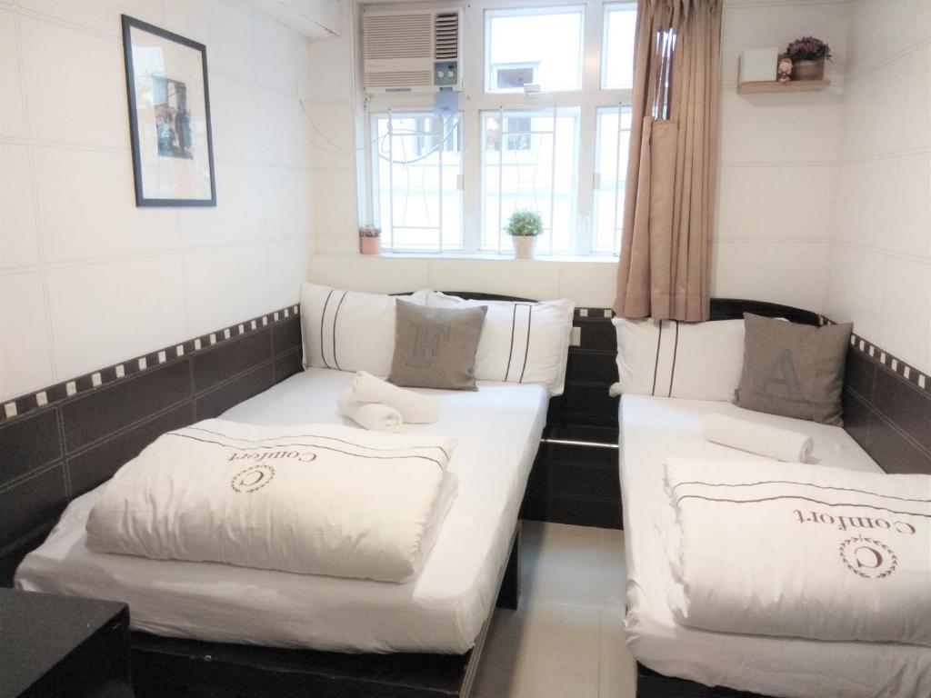 2 camas en una habitación pequeña con ventana en Happy Bee Hostel, en Hong Kong