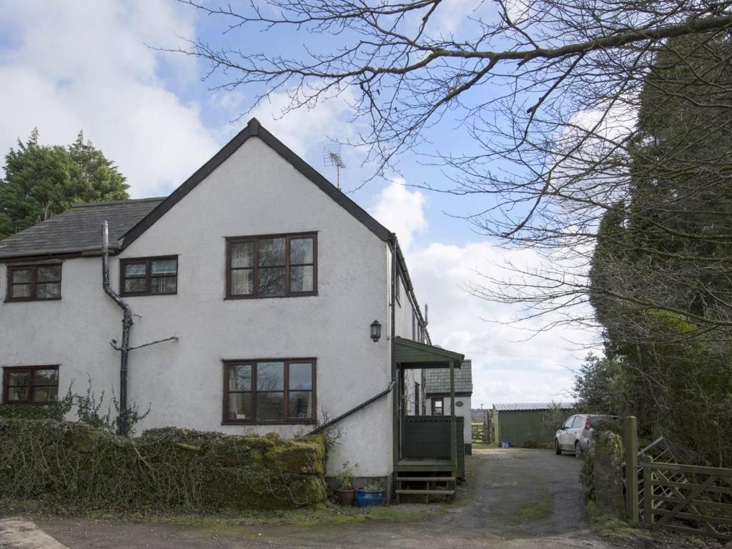 una casa blanca con ventanas negras en una calle en The Annexe, Higher Lydgate Farmhouse, en Postbridge