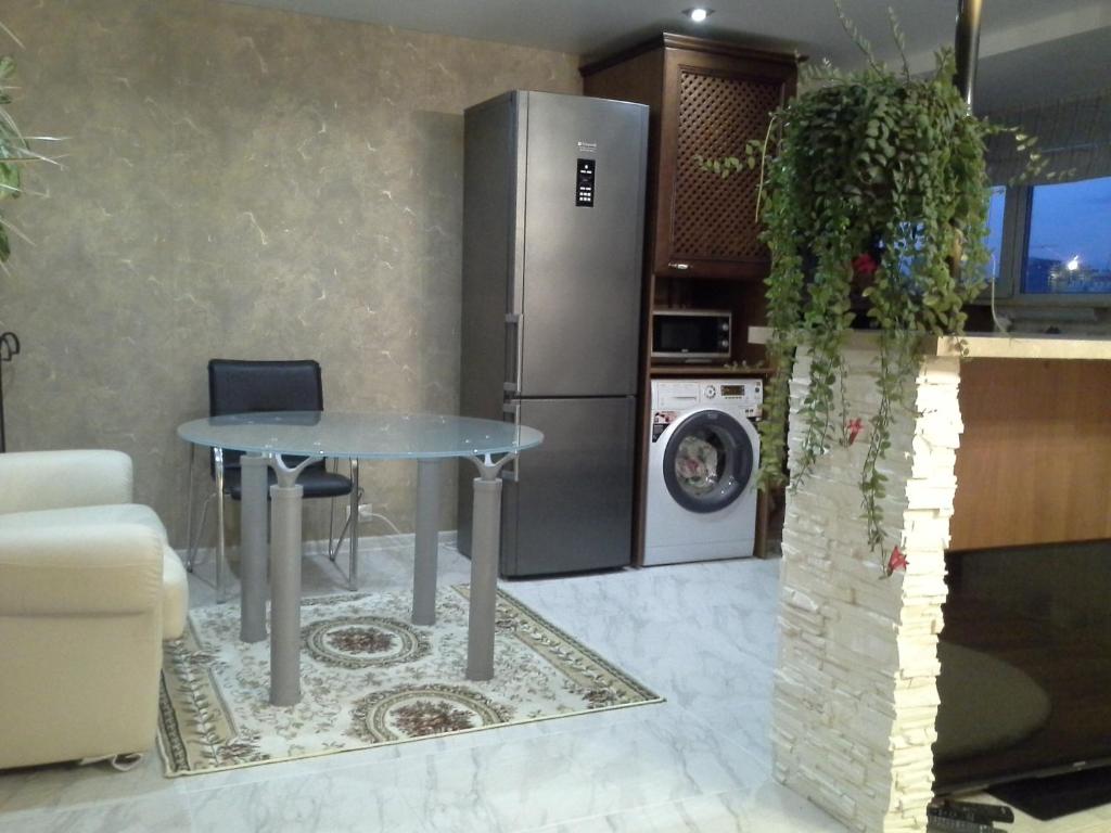 a kitchen with a table and a stainless steel refrigerator at Аппартаменты с видом на залив in Cheboksary