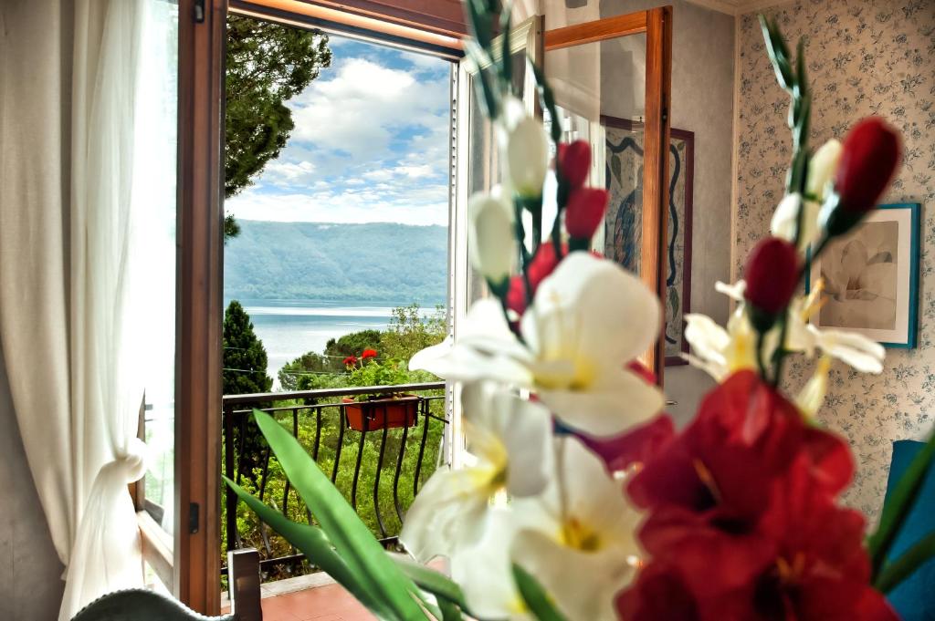 a window with flowers and a view of the ocean at Villalbert in Castel Gandolfo