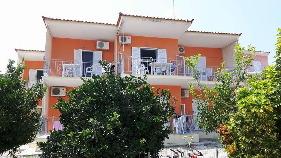 an orange building with white chairs on a balcony at Maria Gerokonstanti Studios in Elliniká