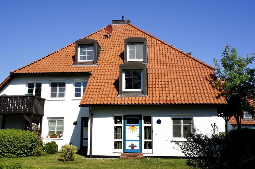 une maison blanche avec un toit orange dans l'établissement Feriendomizil Prerow, à Prerow