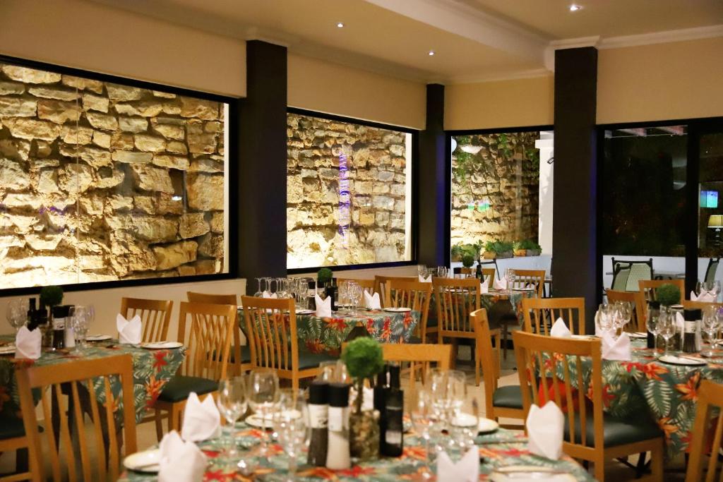 a dining room with tables and chairs and a stone wall at Park Hotel Mokopane in Mokopane