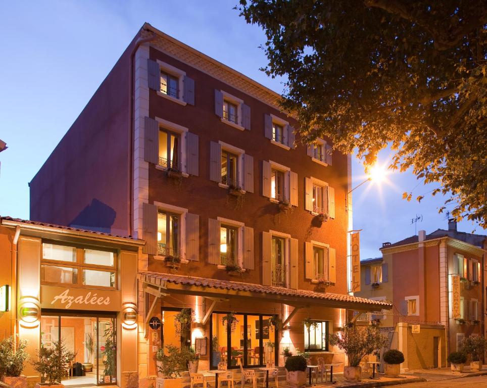 ein Gebäude auf einer Straße mit Tischen davor in der Unterkunft Logis Hôtel Restaurant Azalées in Tournon-sur-Rhône