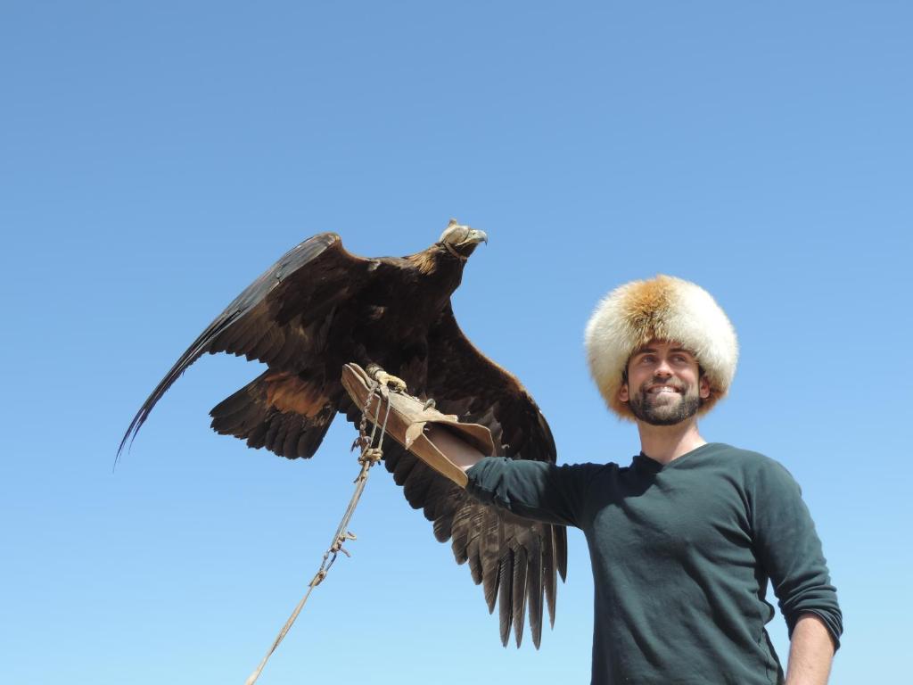 Ein Mann hält einen Raubvogel in der Unterkunft Guesthouse Gulmira in Bokonbayevo