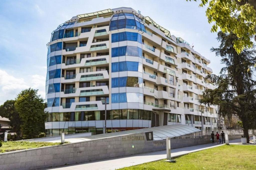 a tall white building with blue windows at Super Central Luxury Apartments in Burgas
