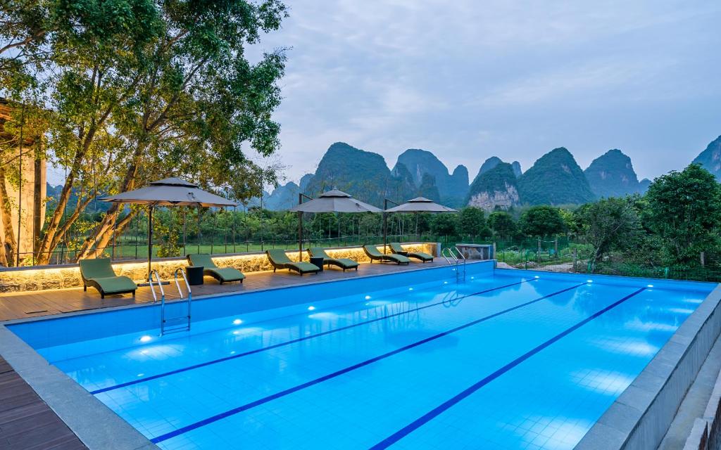 a swimming pool with mountains in the background at Moon Villa in Yangshuo