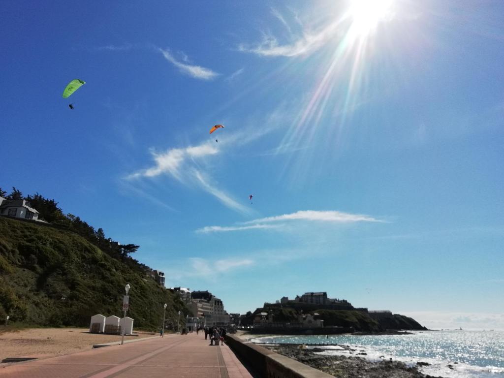 people walking on the beach with kites in the sky at L'escale Granvillaise in Granville