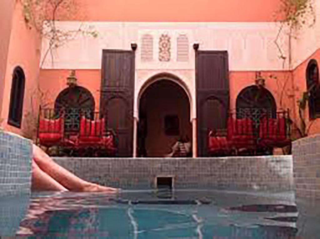 a swimming pool with red chairs in a building at Riad La Perle de Marrakech in Marrakesh