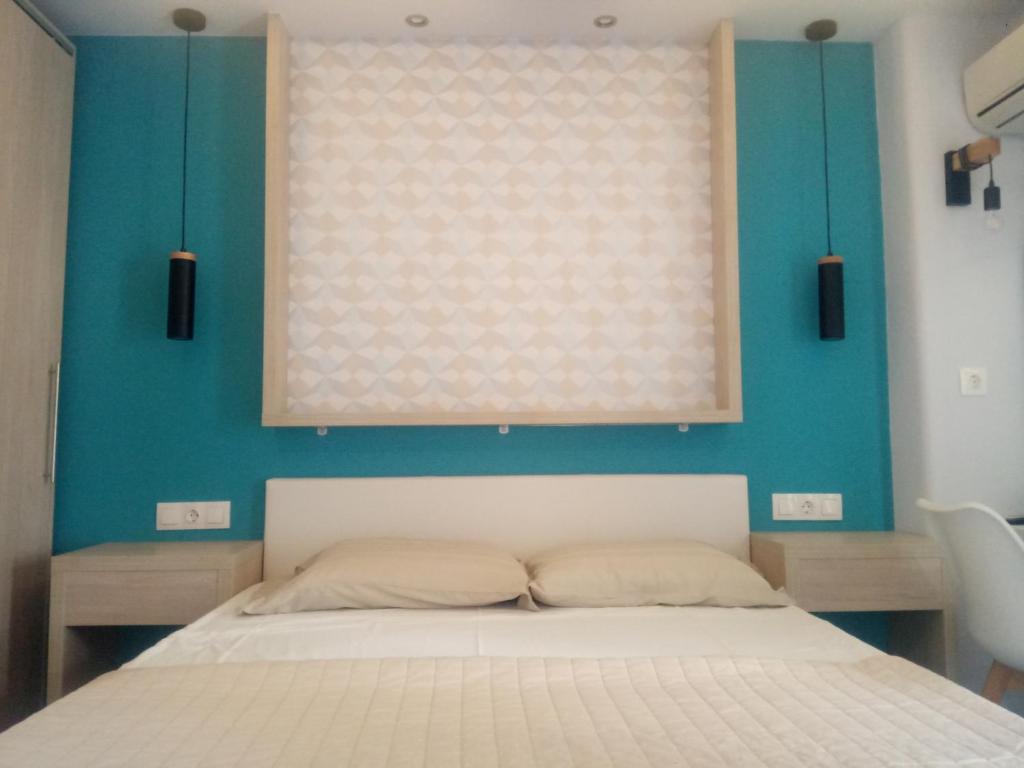 a bedroom with a white bed and a blue wall at Gatos House 2 in Pefkohori