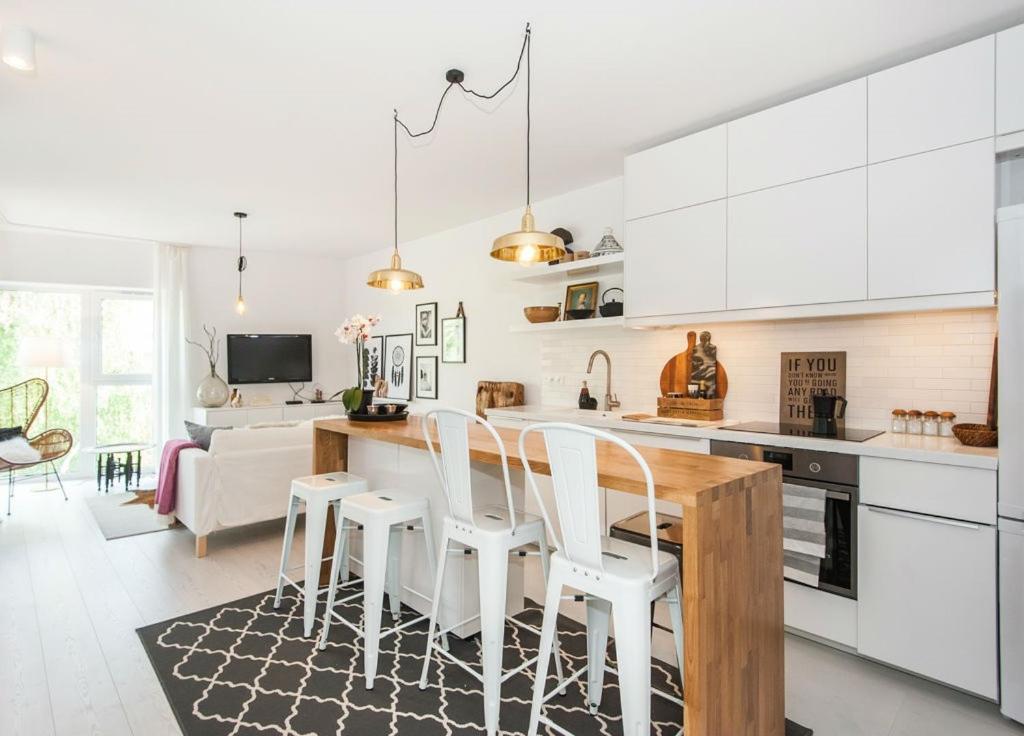 una cucina con armadi bianchi, tavolo e sedie di Super-Apartamenty Exotic a Poznań